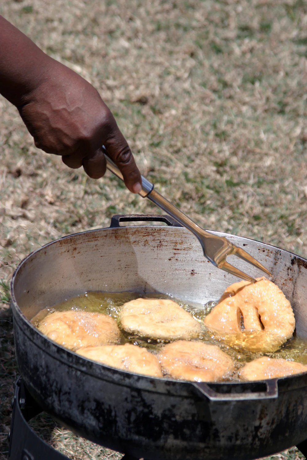 Rounds of dough puffing up as they fry in a pan of oil